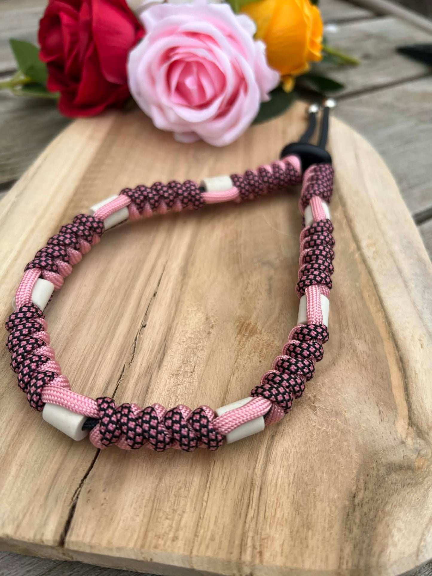 Gros plan sur le tressage torsadé d'un collier naturel pour chien coloris rose et noir