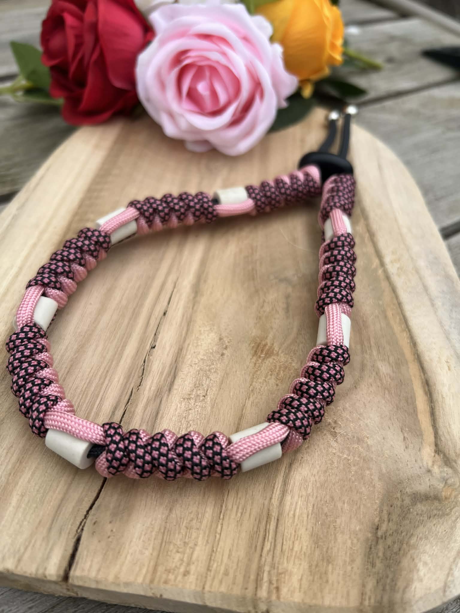 Gros plan sur le tressage torsadé d'un collier naturel pour chien coloris rose et noir